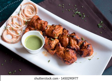 Top angle photo of Chicken Tikka Kebabs served with mint chutney and mayonaise onions on a white rectangular plate. This photo will best suite for print and digital media. 