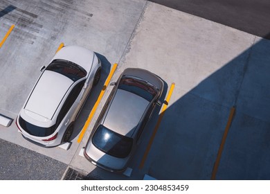 Top Angle View of 2 Cars Parked on outdoor Parking Lots area in front of building with Sunlight and Shadow on surface