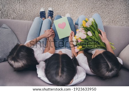 Top angle view full size portrait of three persons sit on sofa arms touch hold card flowers free time home indoors