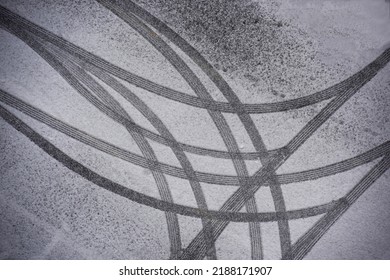 Top angle view of snow covered asphalt parking lot with curved and straight wheel traces, South Korea 
