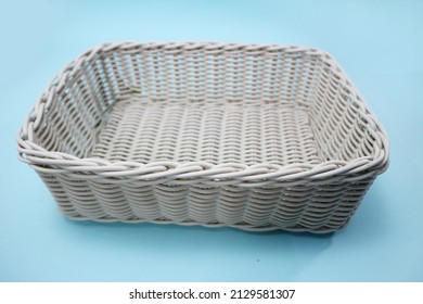 Top angle of a white plastic container which is similar to a rattan basket, with a blue background.