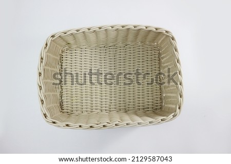 Top angle of a white plastic container which is similar to a rattan basket, with a white background.