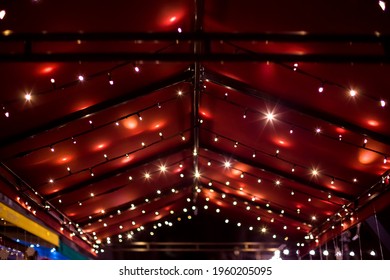 Top Of The Canopy In A Red Textile Gazebo With String Light Garlands Decorative Holiday Lighting Roof Terrace Night Scene.