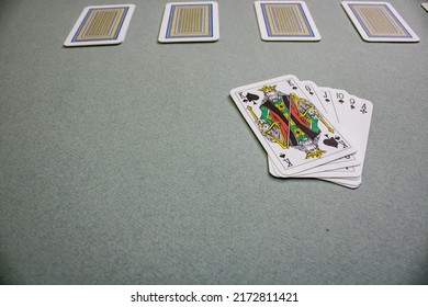 The Top Cards Are Face Down, The Bottom Ones Are Face Up And Playing Cards On The Bottom Right, Lined Up On The Green Table.