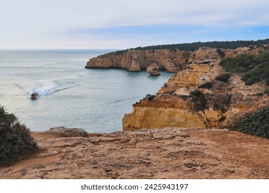 Top of cliffs over a boat in the Atlantic Ocean on a winter day in southern Portugal.