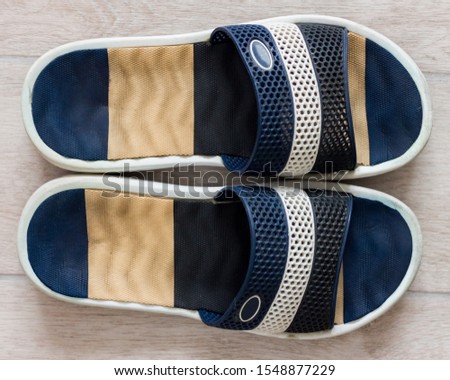 Top close up view of men's rubber slippers on wooden floor background. Multicolor Slippers for the sea.