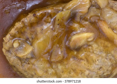 Top Close View Of A Microwaved Salisbury Steak With Mushrooms And Onions In Gravy.