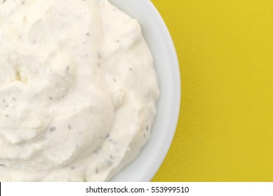 Top Close View Of  A Small Bowl Filled With Fresh French Onion Dip Atop A Bright Yellow Tablecloth.