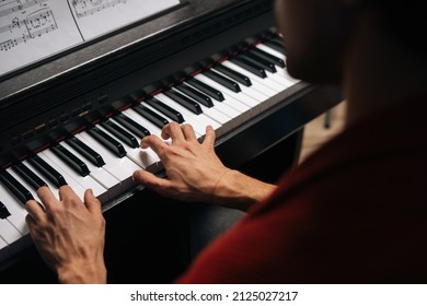 Top close-up view of hands of unrecognizable musician man playing on piano at home during lesson. Closeup back view of pianist male playing digital electronic synthesize. Concept of music education. - Powered by Shutterstock