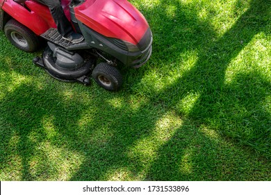 Top Down Above View Of Professional Lawn Mower Worker Cutting Fresh Green Grass With Landcaping Tractor Equipment Machine. Garden And Backyard Landscape Lawnmower Service And Maintenance