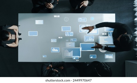 Top down aerial of collaborate professional diverse business people discuss marketing strategy with hologram of marketing data analysis graph, diagram or financial profit investment plan. Directorate. - Powered by Shutterstock