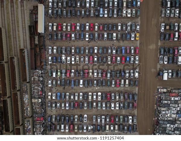 Top down aerial drone image of a junk yard\
with row after row of wrecked\
cars.