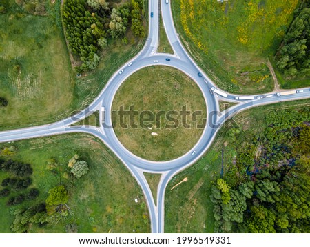 Top down aerial drone view of a small traffic roundabout on a quiet road