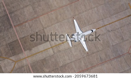 Top down aerial drone view of a private jet parked at an airfield. Business plane at airport terminal