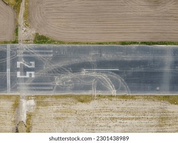 Top down aerial shot of a section of disused runway at Woodford Aerodrome, United Kingdom with vegetation to the sides - Powered by Shutterstock