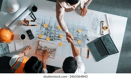 Top down aerial view of architect engineer team shake hands and discussing about building construction. Group of diverse people working together to plan and design by using blueprint. Alimentation. - Powered by Shutterstock