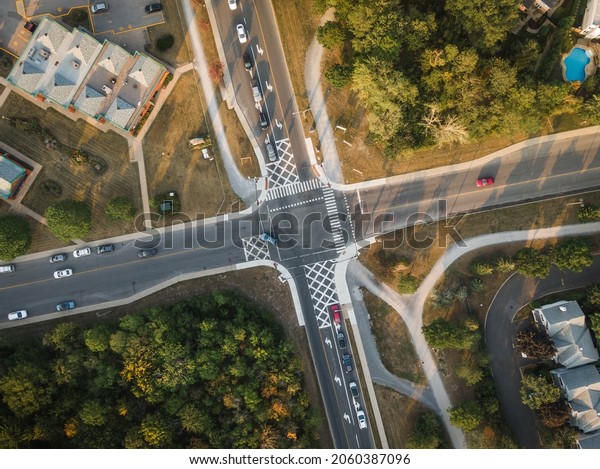 Top down aerial view of cars driving through\
intersection at sunset in residential neighbourhood in Montreal,\
Quebec, Canada, North America.\
