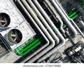 Top down aerial view of complex industrial silver and green pipelines.