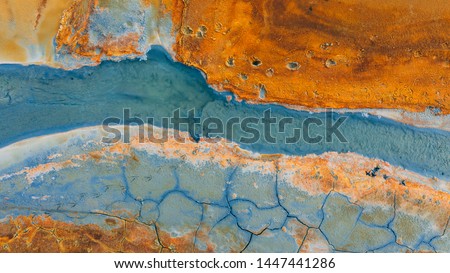 Top down aerial view from drone on geothermal icelandic in Iceland Seltun  Krysuvik Kleifarvant lake blue water and orange ground texture structure hot spring mud background foot prints animals birds