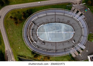 Top Down Aerial View Of Empty Oval Office Building With Glass Middle Part. Modern Contemporary Exterior Facade Building Seen From Above.