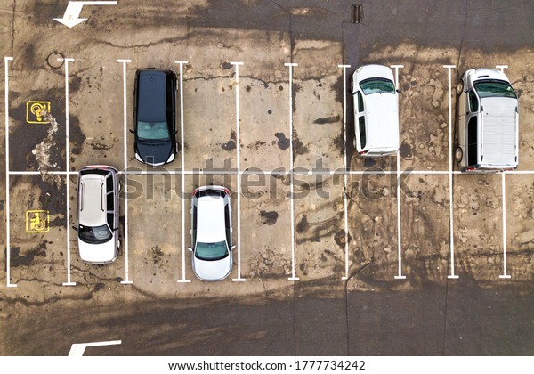 Top down aerial view of many cars\
on a parking lot of supermarket or on sale car dealer\
market.
