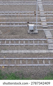 Top down aerial view of multiple parallel railway tracks with gravel ballast, concrete sleepers, and junction box at depot

