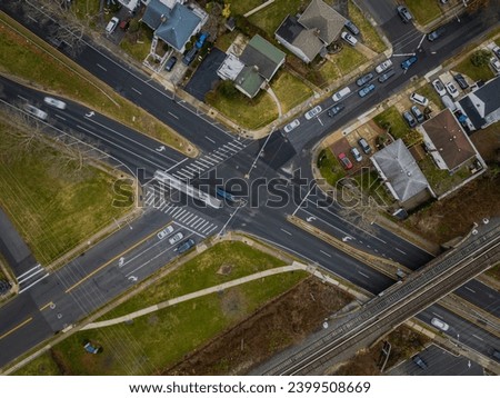 A top down, aerial view over a suburban neighborhood intersection on Long Island, New York on a cloudy day.