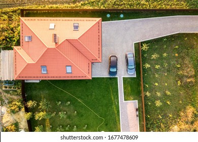 Top Down Aerial View Of A Private House With Red Tiled Roof And Spacious Yard With Parked Two New Cars.