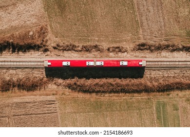 Top Down Aerial View Of Red Passenger Train Riding Through Countryside Landscape