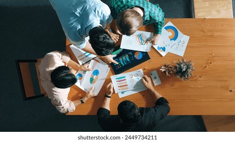 Top down aerial view of smart business people analyze data together at meeting. Group of business team working together and looking at financial chart at tablet placed on meeting table. Convocation. - Powered by Shutterstock