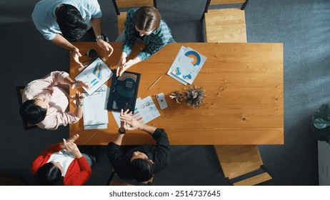 Top down aerial view of smart business people analyze data together at meeting. Group of business team working together and looking at financial chart at tablet placed on meeting table. Convocation. - Powered by Shutterstock