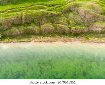 Top down aerial view of surrealistic landscape near calm green water