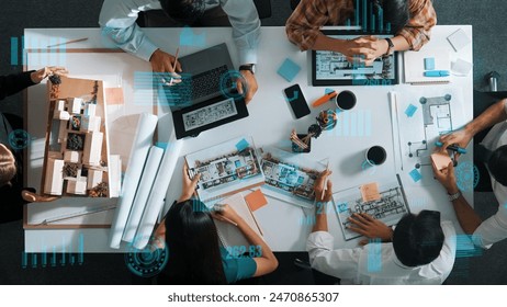 Top down aerial view of team looking at blueprint and talking about financial chart or investment statistic holographic. Aerial view of project manager discussing and brainstorming idea. Alimentation. - Powered by Shutterstock