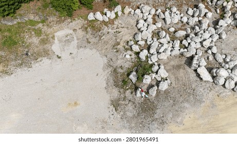 Top down aerial view of two unrecognizable people standing among large limestone boulders with open gravel copy space