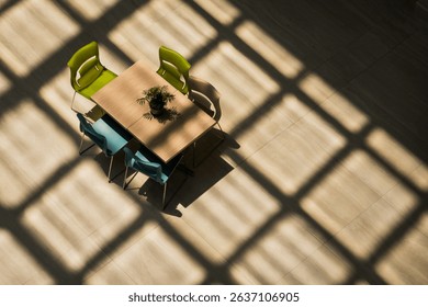 A top down bird's eye view of a public table is seen inside a building under the shadow of a glass roof. 