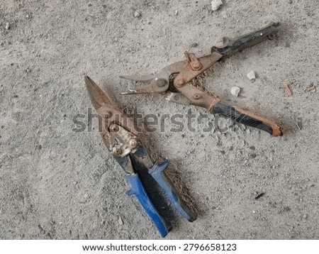 A top down close up shot of a pair of rusty aviation snips and tin snips on a rough dusty concrete background for sheet metal and roof construction work