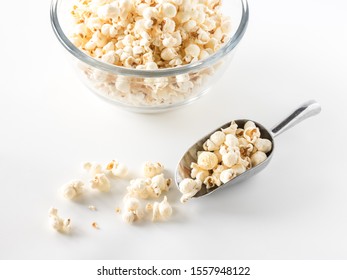 A Top Down Close Up View Of A Bowl Of White Cheddar Popcorn With A Scoop Of Popcorn In Front.