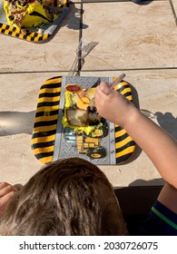 Top Down, Close Up View Of A Digging, Bulldozer Themed Birthday Cake. The Vanilla Cake Has A Stop Sign On It And A Young Boy Is Holding A Plastic Fork To Eat His Dessert At The Full Table