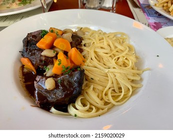 The Top Down, Close Up View Of A Dish Filled With Freshly Served Boeuf Bourguignon With A Side Of Pasta.