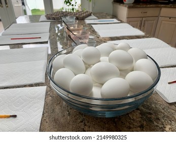 The Top Down, Close Up View Of A Kitchen Counter Set Up For Kids To Paint Easter Eggs. There Are Paper Towels, Paint Brushes, Empty Egg Cartons, Hard Boiled Eggs, And Dying Stations.