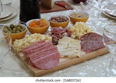 The Top Down, Close Up View Of A Meat And Cheese Platter On Top Of A Dining Room Table. There's A Variety Of Pickings And A Bottle Of Red Wine Next To The Cutting Board.