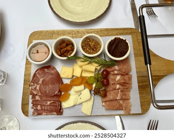 The top down, close up view of a meat and cheese platter. There are deli meats, dried fruits, cheese, bread, and different spreads. - Powered by Shutterstock