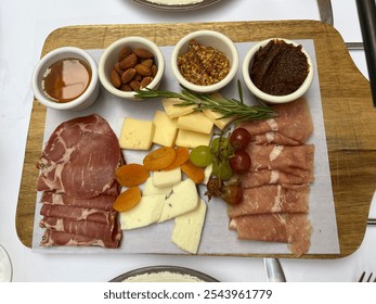 The top down, close up view of a meat and cheese platter. There are deli meats, dried fruits, cheese, bread, and different spreads. - Powered by Shutterstock