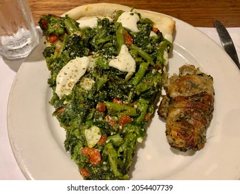 The Top Down, Close Up View Of A Plate In A Pizzeria. There Is A Broccoli Rabe Slice Of Pizza With A Spinach Garlic Knot. 