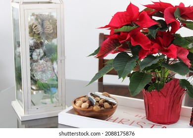 The Top Down, Close Up View Of A Tray Sitting On Top Of A Kitchen Table. The Tray Reads MERRY CHRISTMAS And Is Holding A Nut Bowl, A Bright Red Poinsettia Plant, And A Lantern Filled With Green Balls.