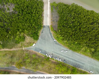 Top Down Drone Aerial Over A Car Park Beside A Boat Ramp On A Tidal River With Forested Shoreline