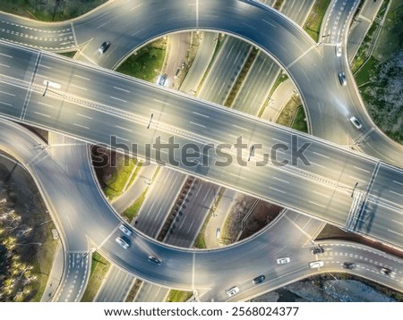 Top down drone photo of circular highway interchange during the night, with streetlights on