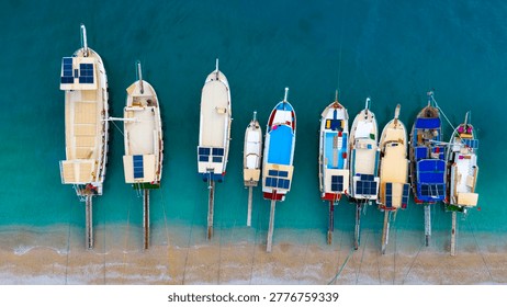 Top down drone view capturing an impressive array of colorful excursion boats anchored tightly together at the edge of a pristine holiday beach destination.