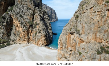 Top down drone view of dramatic rocky coast and natural stone arch with turquoise Mediterranean waves crashing below near Mallorca island.