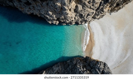 Top down drone view of dramatic rocky coast and natural stone arch with turquoise Mediterranean waves crashing below near Mallorca island.